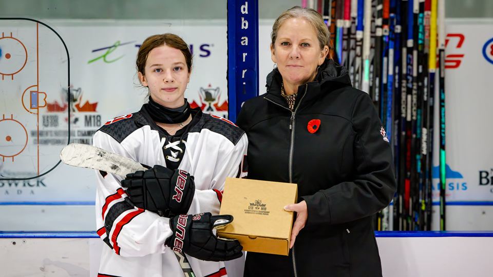 Kendall Doiron receiving the player of the game award from Host Committee chair Dana Purton Dickson.