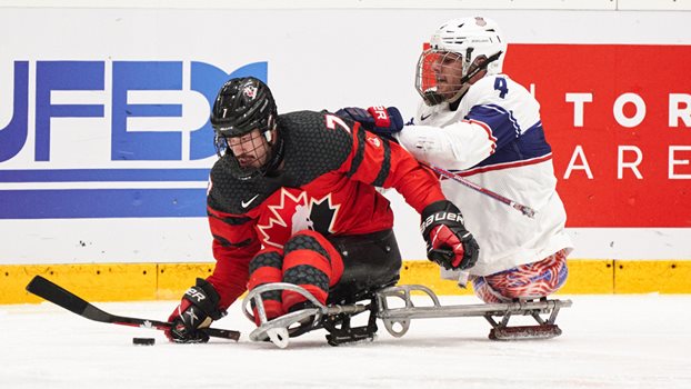 Le joueur de l’équipe nationale de parahockey Zach Lavin contrôle la rondelle alors qu’il est mis en échec par le joueur américain Brody Roybal.
